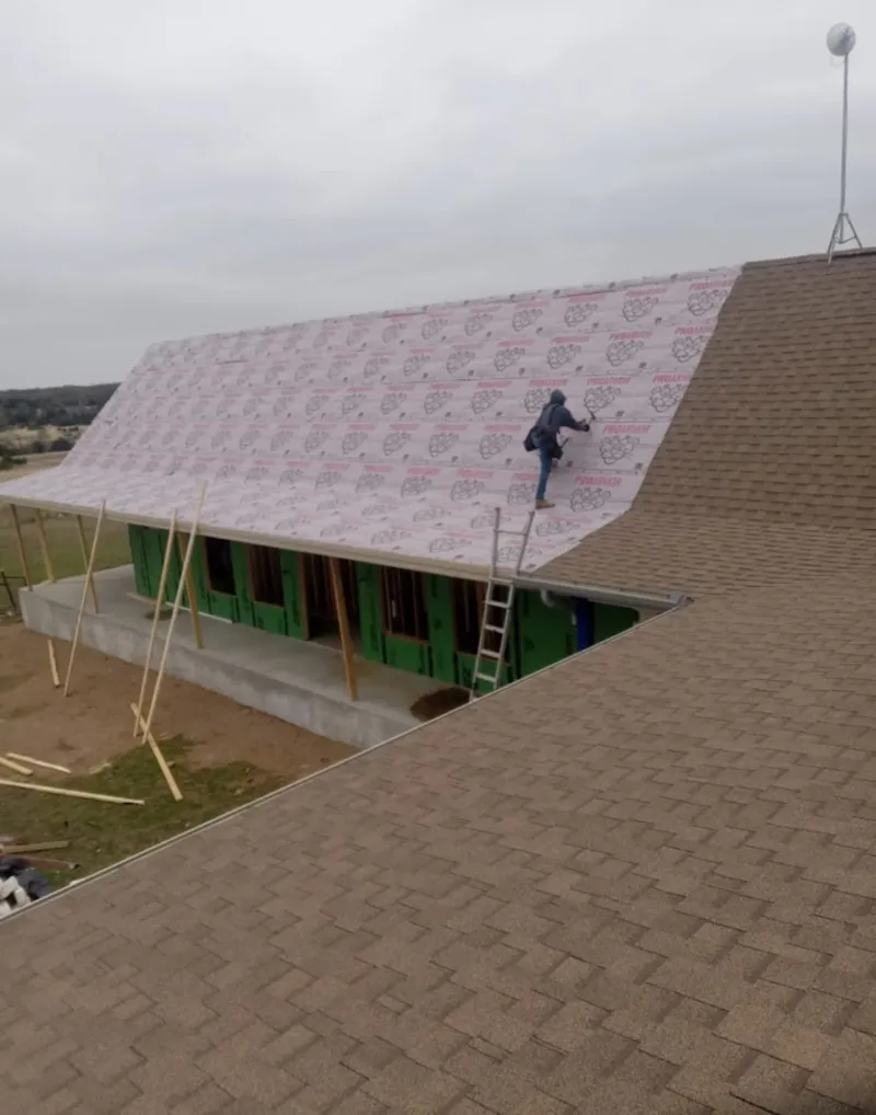 Worker preparing underlayment for a metal roof installation in Rochelle Park